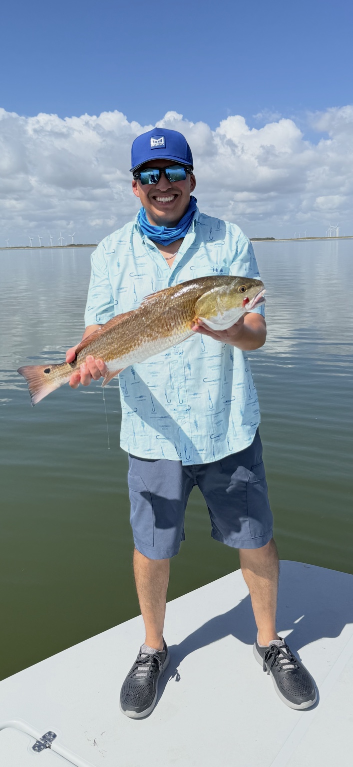 Smiling angler holding a redfish on calm South Texas water