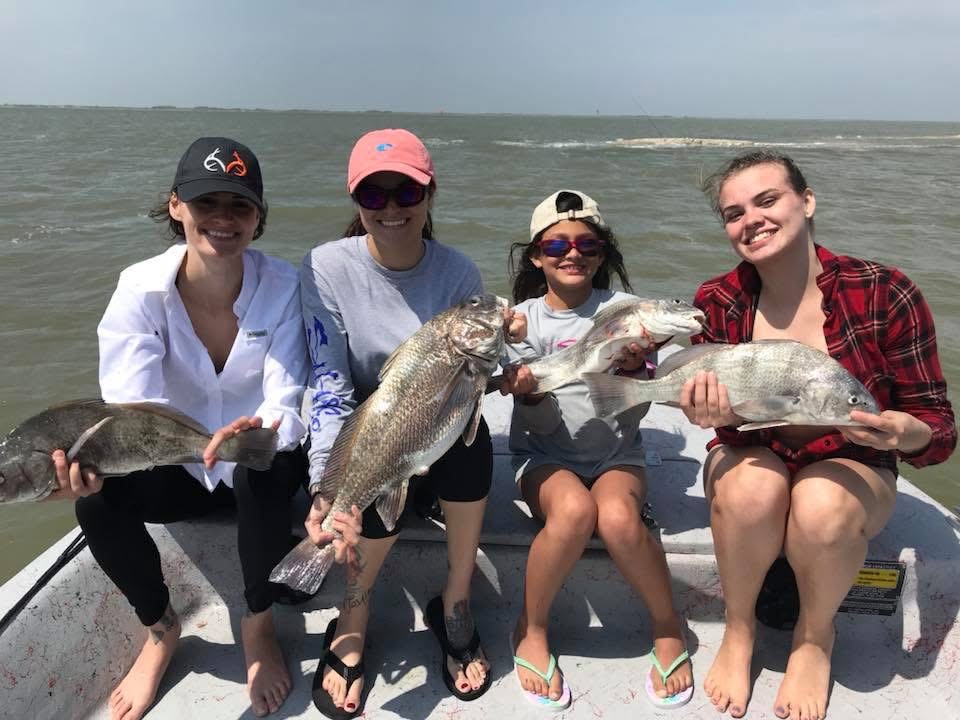 Four women holding black drum on a fishing boat