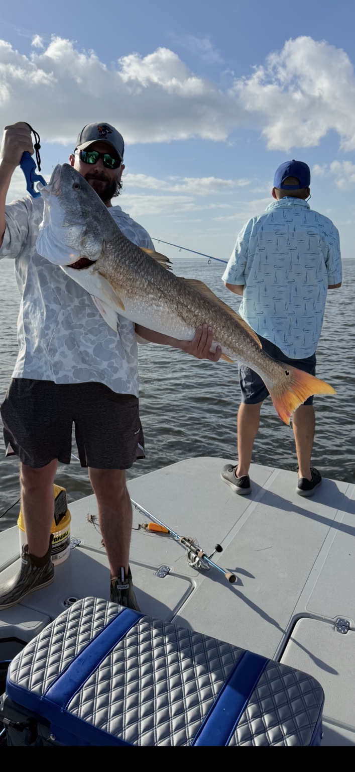 Angler holding a large redfish aboard a South Texas fishing boat
