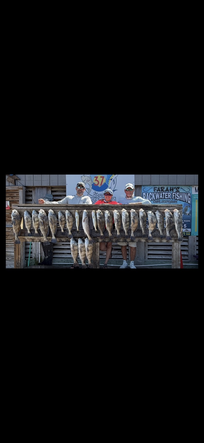 Three anglers behind a full rack of fish