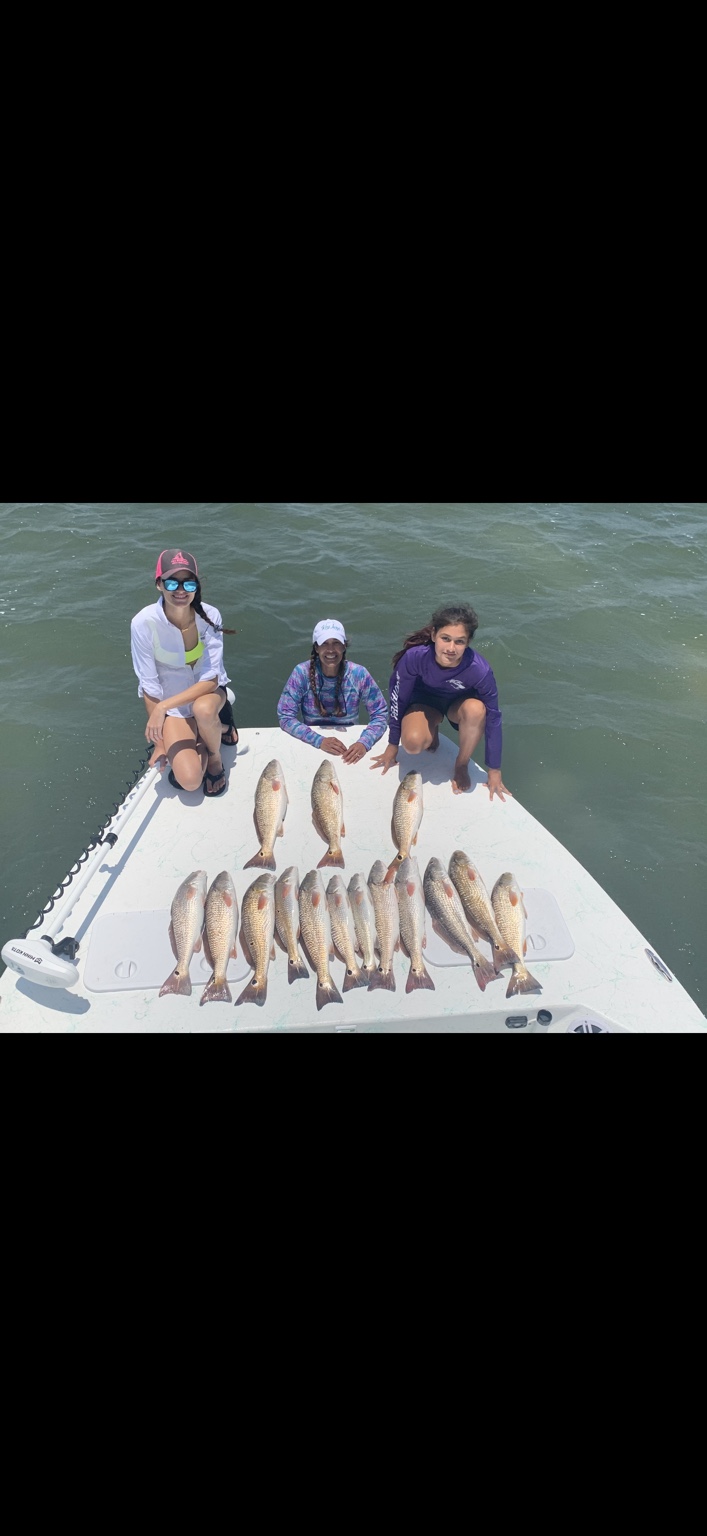 Three anglers on the bow with a lineup of redfish