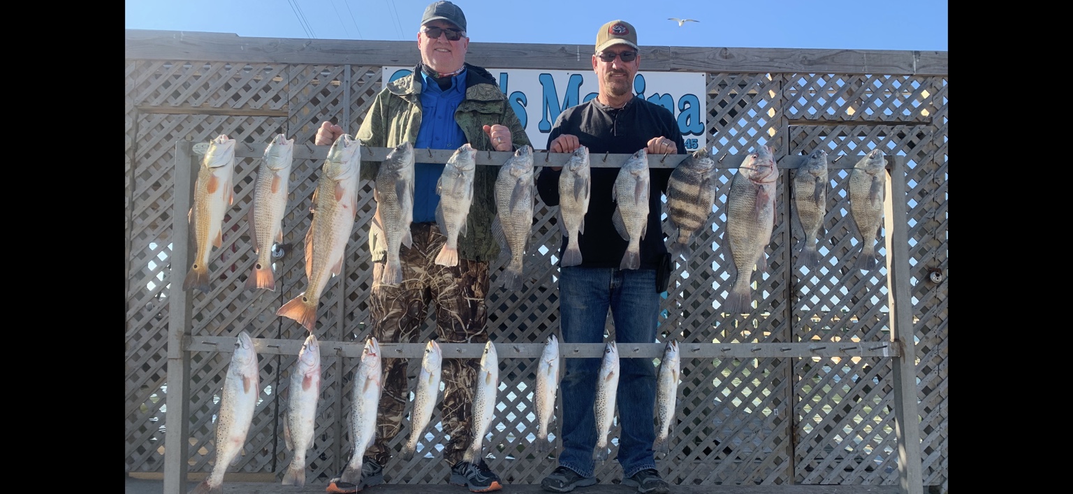 Two anglers behind a full rack of redfish, black drum, and speckled trout at Clem's Marina