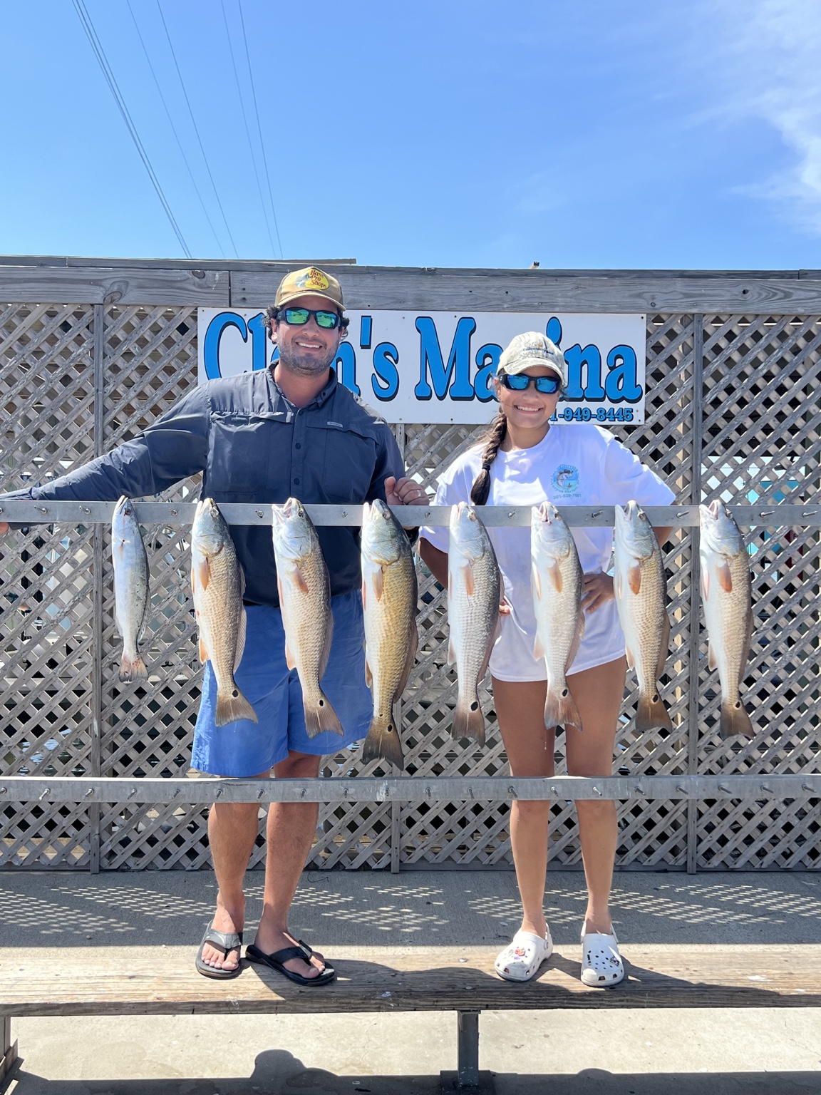 Two anglers behind a rack of redfish at the marina